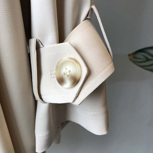 Close-up of a beige Plus Size Winter Coat for Women with a button on a light gray background