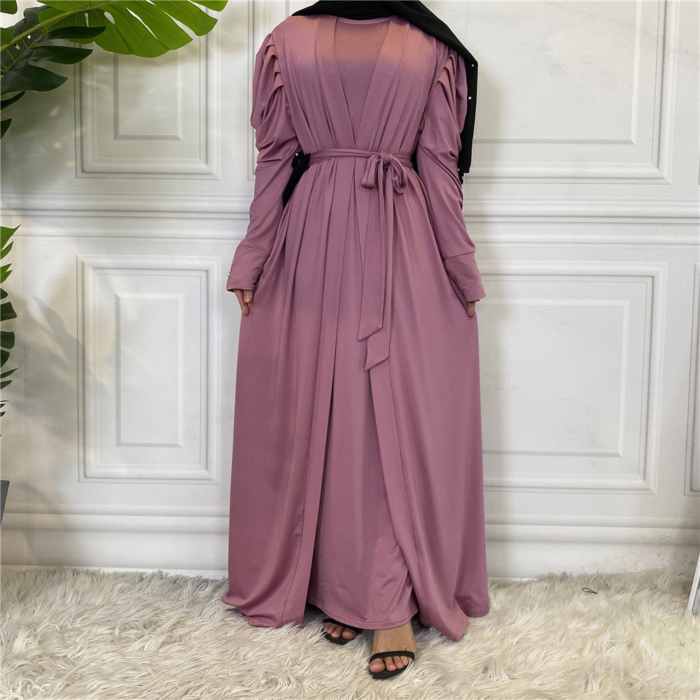 Person wearing a long mauve dress against a white paneled wall.