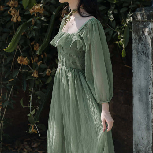 Person wearing a Green Ruffle Maxi Dress standing against a natural background with plants.
