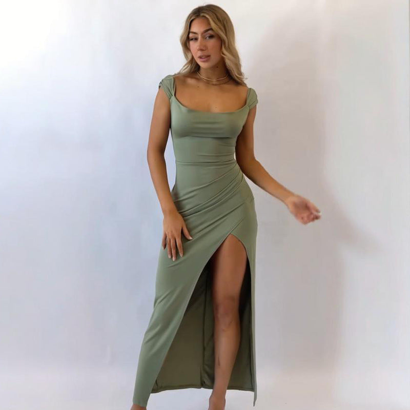 Woman wearing a green dress with a slit on a plain background