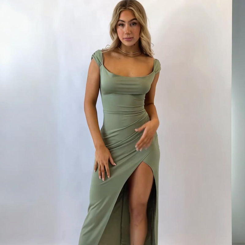 Woman wearing a green dress with a slit on a plain background