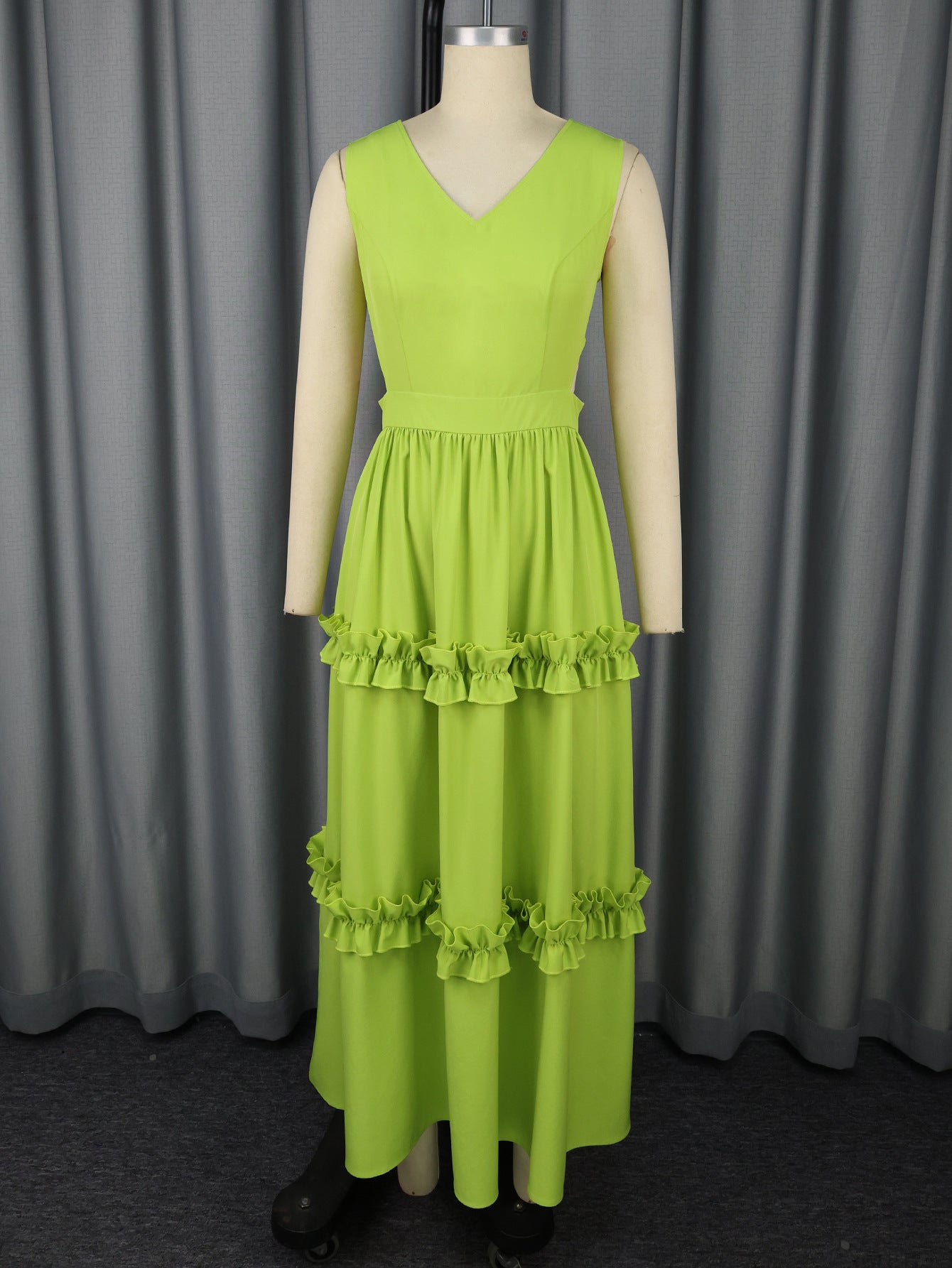 Green dress on a mannequin against a gray curtain background