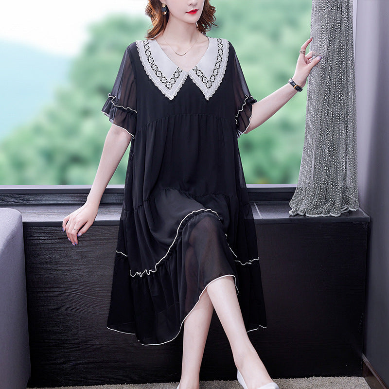 Woman in a black dress with white lace details sitting on a window ledge.