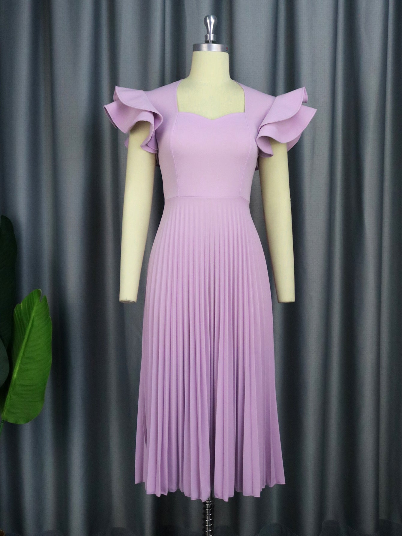 Purple dress on a mannequin against a gray curtain background