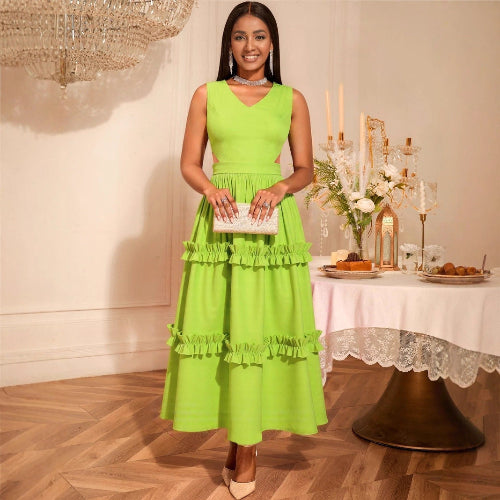 Woman in a High-Waist Mustard Green Dress standing in a decorated room with a table and flowers.