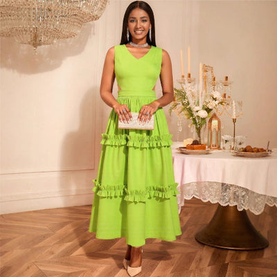 Woman in a High-Waist Mustard Green Dress standing in a decorated room with a table and flowers.