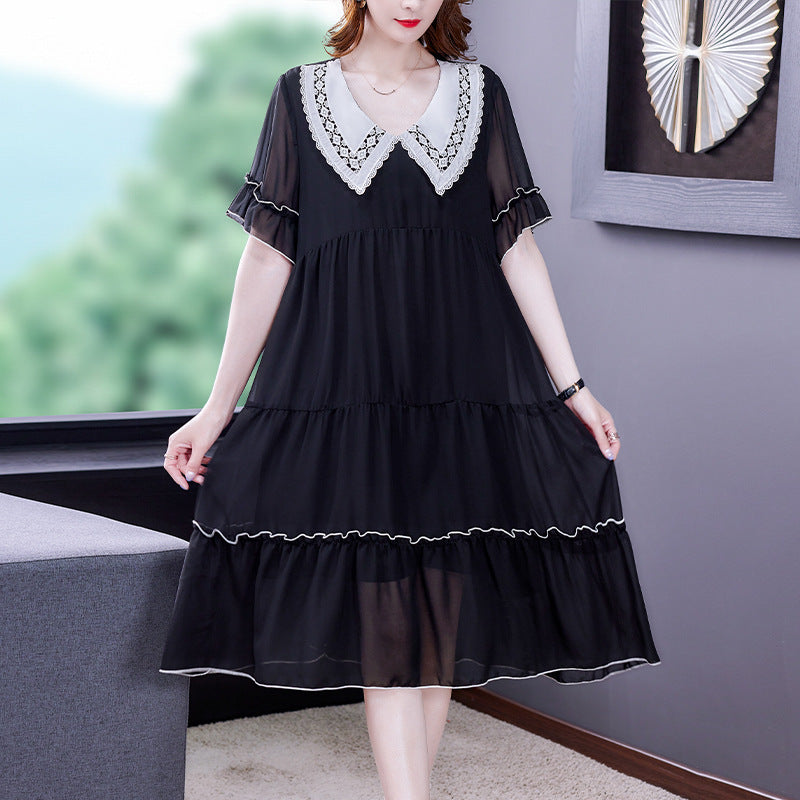 Woman wearing a black dress with white lace details in an indoor setting.