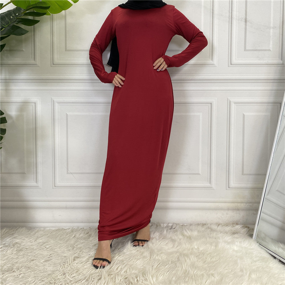 Person wearing a red dress standing against a white paneled wall.