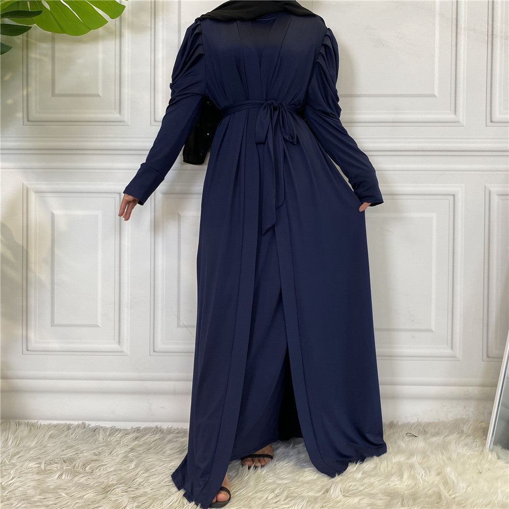 Person wearing a navy blue dress with a hood against a white paneled wall.