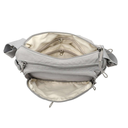 Gray crossbody bag with multiple zippers on a white background
