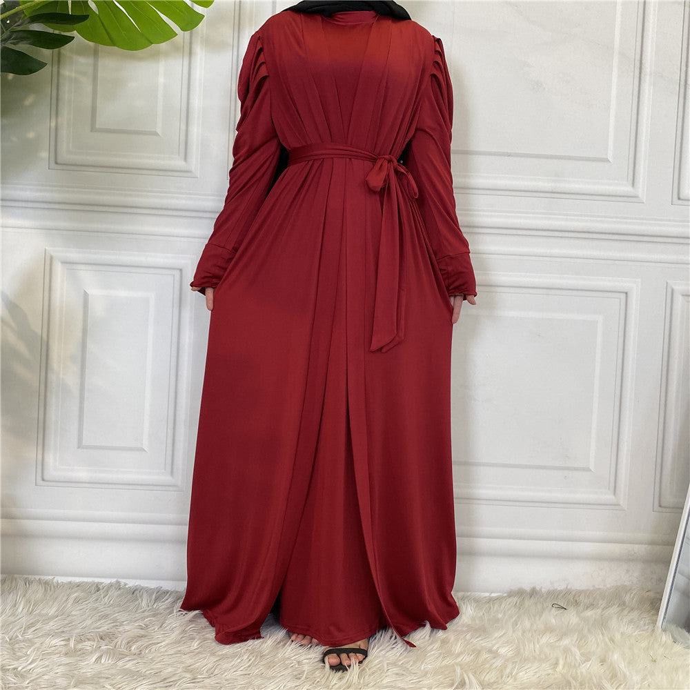 Red dress with long sleeves and a belt on a white paneled wall.
