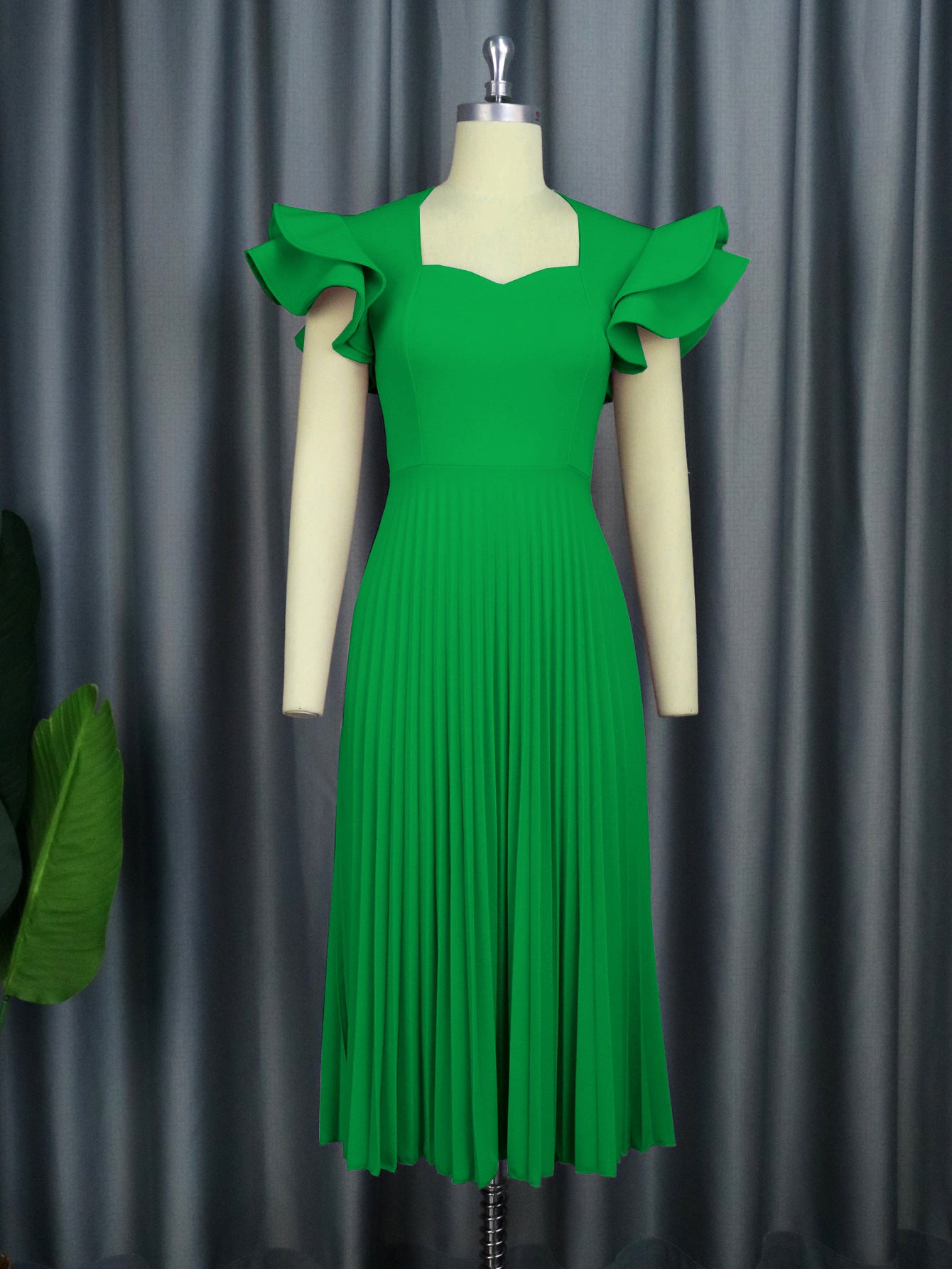 Green dress on a mannequin against a gray curtain background