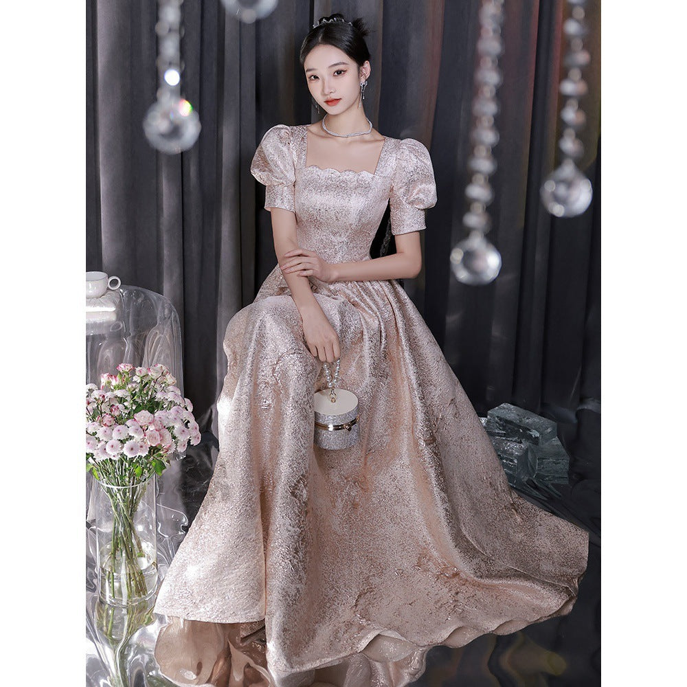 Woman in a sparkling evening gown holding a small handbag in a decorated room.