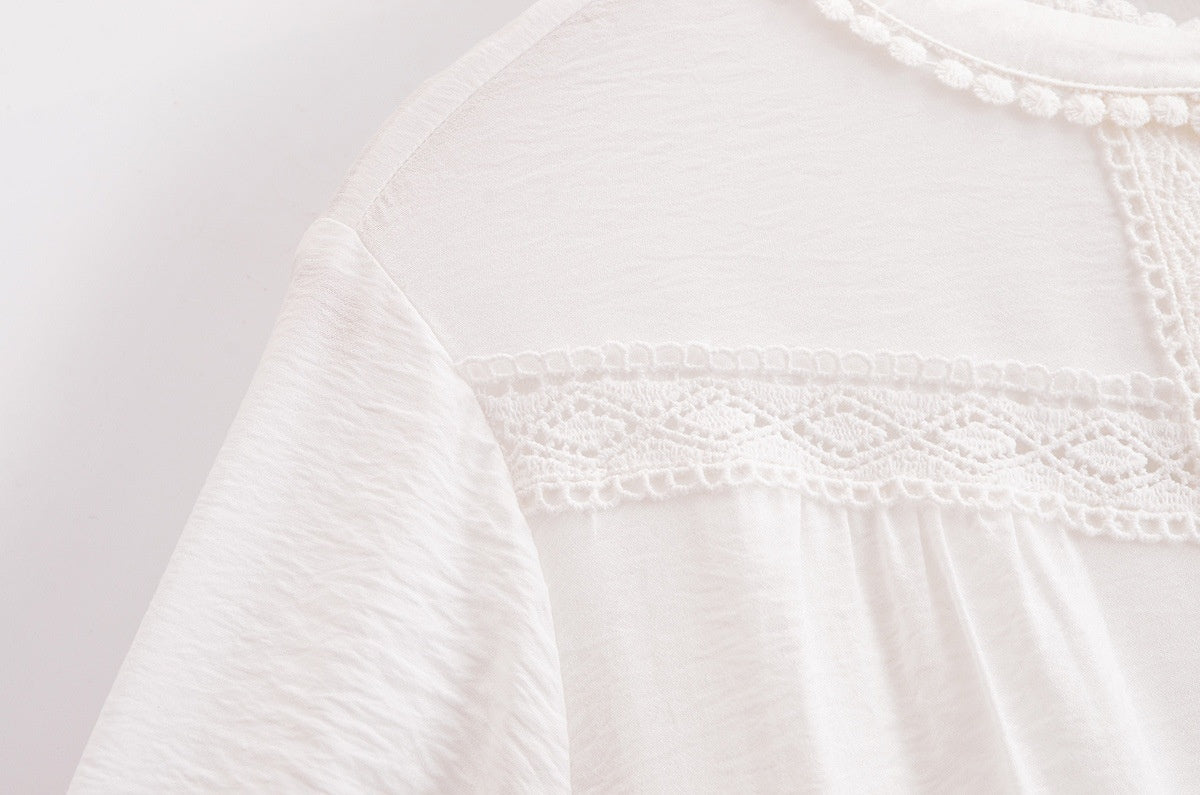 Close-up of a white garment with intricate lace detailing on a light pink background