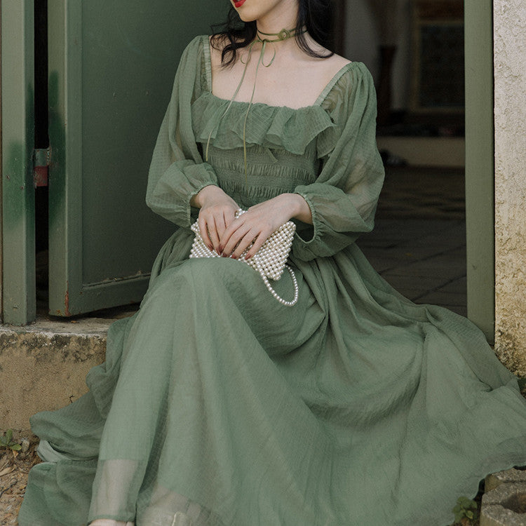 Women's Temperament Fashion Dresses. Woman in a green dress sitting on steps holding a pearl-handled clutch.