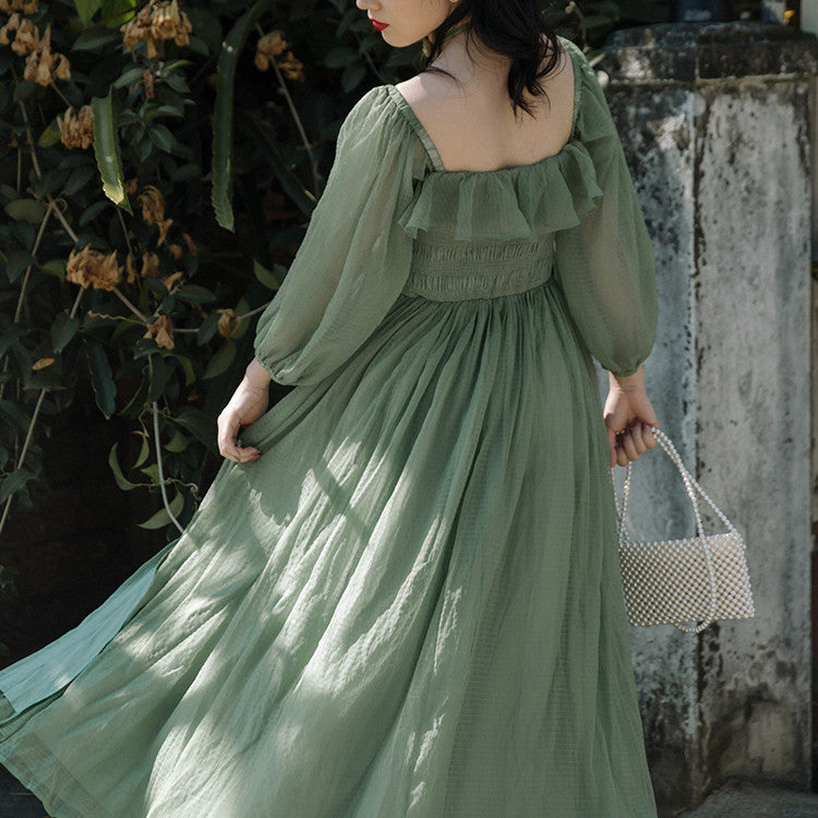 Women's Temperament Fashion Dresses. Woman wearing a green dress holding a small bag against a natural background