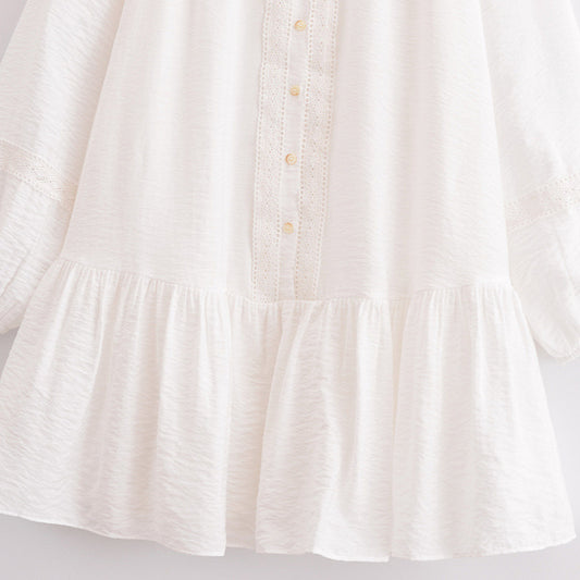 Close-up of a white dress with ruffled hem on a light gray background