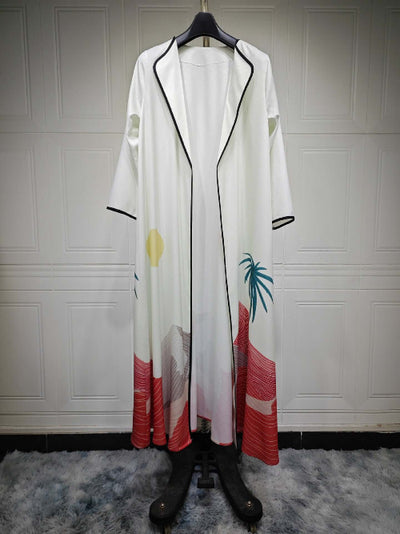 Long white Modest Floral Style Abaya with black trim and colorful design on a hanger against a white paneled wall.