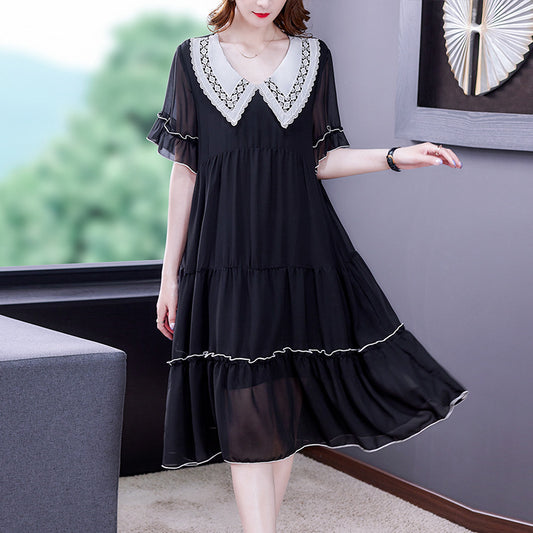 Woman wearing a black dress with white lace details in an indoor setting.